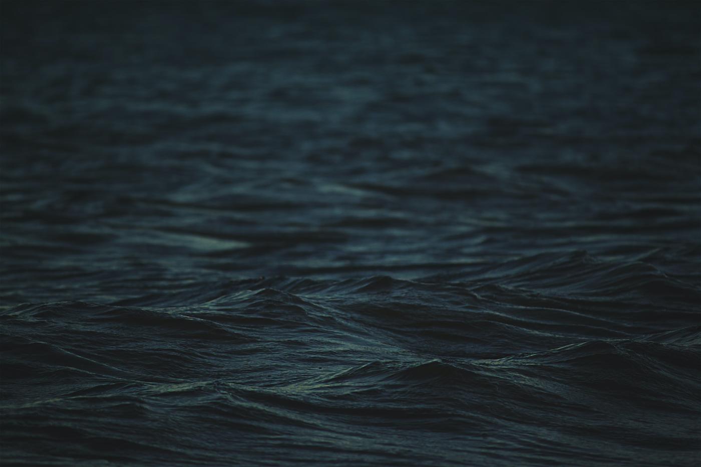 Dark water moving in long low swells under a flat sky