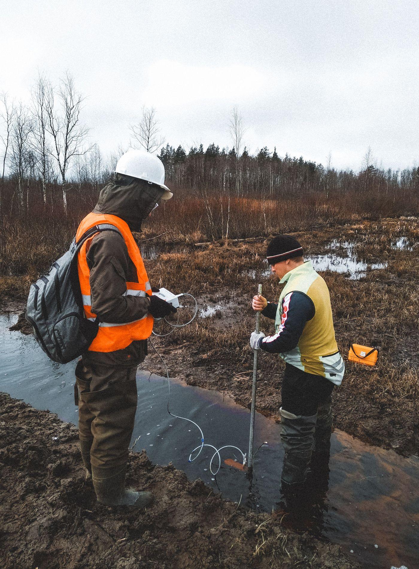 Two researchers wading through shallow water, taking readings on site